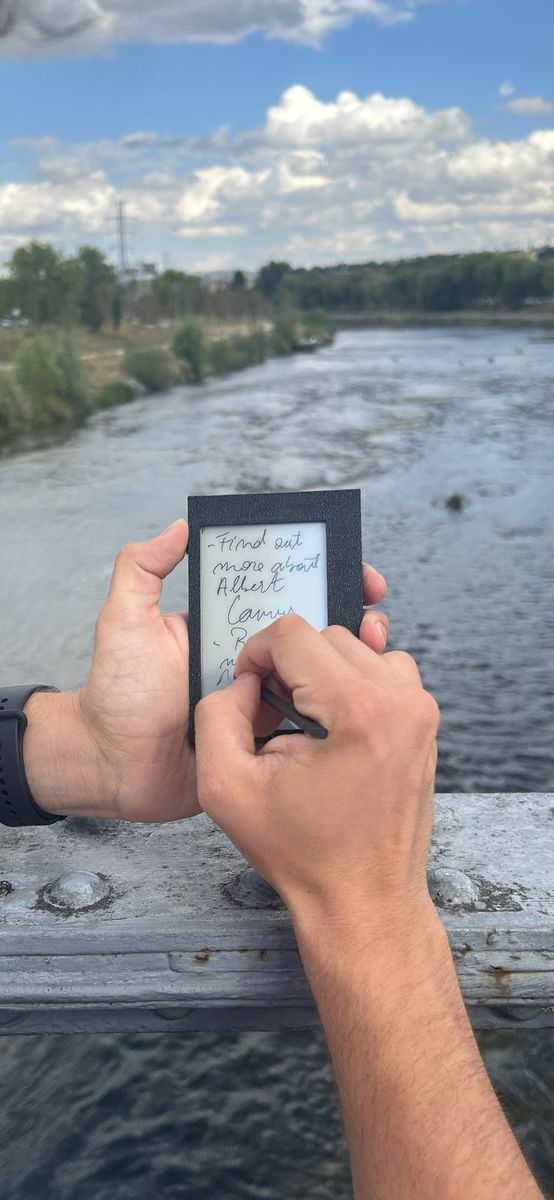 Writing a note on Kairon on a bridge, outdoors